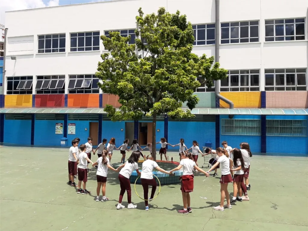 Alunos em roda no pátio, embaixo da árvore